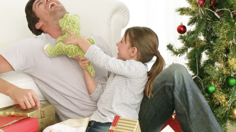 Playful Father and Daughter Enjoying Christmas Morning by Tree