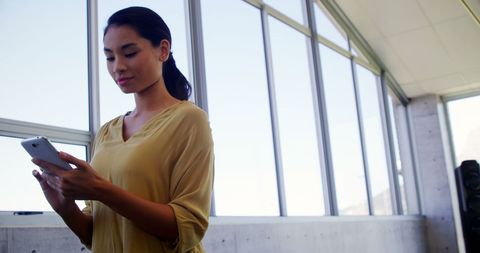 Young Asian Woman Engaging with Smartphone in Modern Interior