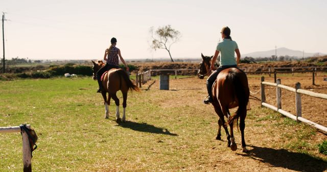 Two individuals are enjoying a leisurely horseback ride in a rural setting, with copy space. The scene captures the essence of outdoor recreational activities and the connection between humans and animals.