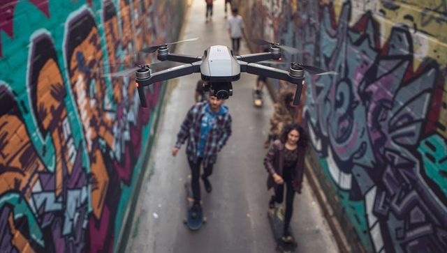 Drone capturing skateboarders riding through graffiti-covered alley