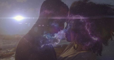 Romantic silhouetted couple embracing by the ocean under celestial sky