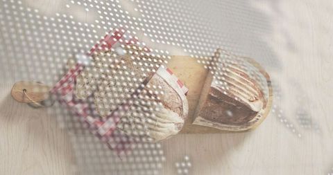 Overhead still life displaying rustic sourdough loaves on wooden paddle with gingham, dotted overlay