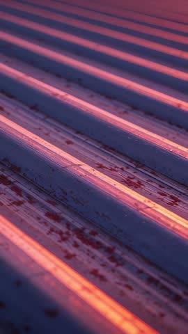 Vertical video revealing rust and texture on corrugated metal rooftop in warm golden light