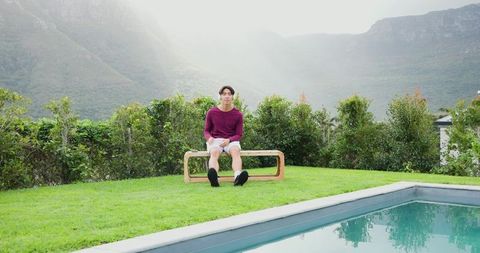 Man Relaxing on Bench Near Pool with Scenic Mountain View