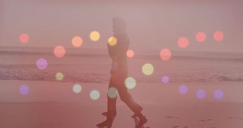 Walking woman leaving footprints on wet shoreline at sunrise with pink bokeh overlay