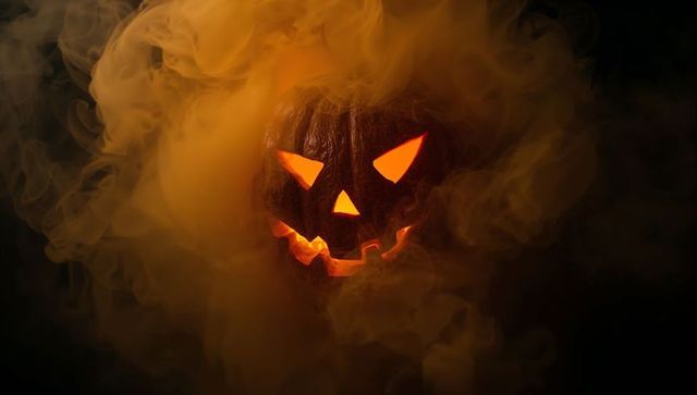 Eerie jack-o'-lantern with glowing eyes amidst smoky atmosphere