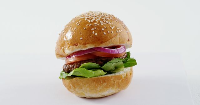 A classic hamburger with lettuce, tomato, and onion on a sesame seed bun is presented against a white background, with copy space. Perfect for showcasing a simple yet appetizing fast-food option.