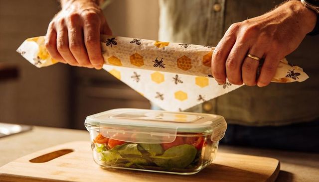 Man wrapping glass food container with beeswax wrap for eco friendly meal prep and storage