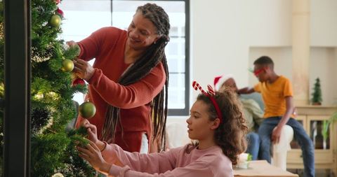 Family Decorating Christmas Tree in Festive Living Room