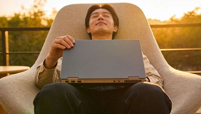 Relaxing at sunset on rooftop lounge chair holding closed laptop, serene outdoor moment