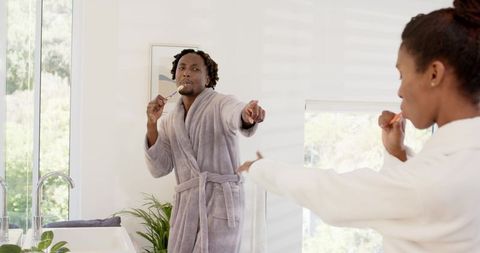Couple brushing teeth together in bright modern bathroom morning routine