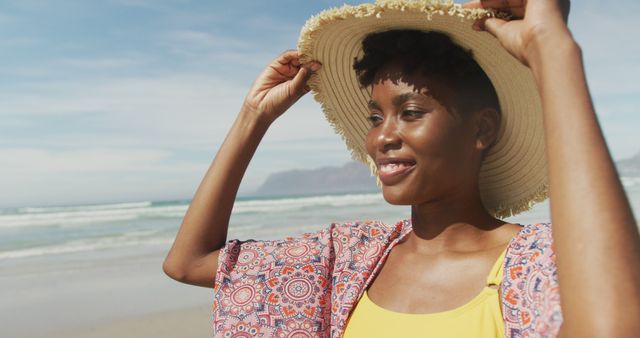 Portrait of happy african american woman with hat on sunny beach. healthy and active time beach holiday.