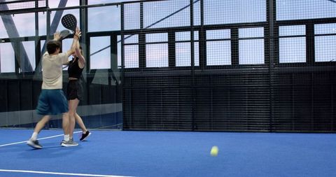 Padel team players celebrating on blue court with racket high-five