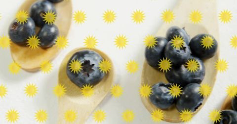 Displaying blueberries on wooden spoons with yellow sunburst pattern overhead food styling