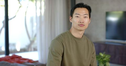 Asian man sitting in modern living room portrait with calm expression and contemporary vibe