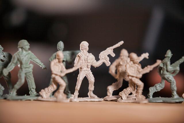 Miniature plastic army soldiers lined up in battle formation, with detailed poses and weaponry, illustrating military strategy and teamwork. Perfect for use in articles or projects related to military tactics, childhood toys, or collector's items.