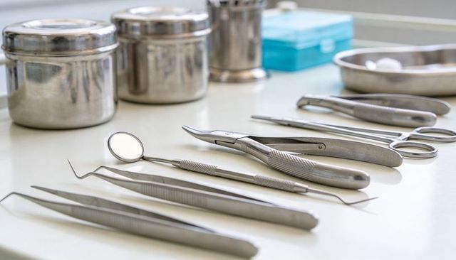 Dental instruments lining sterile clinic countertop with mirror, probes and forceps closeup