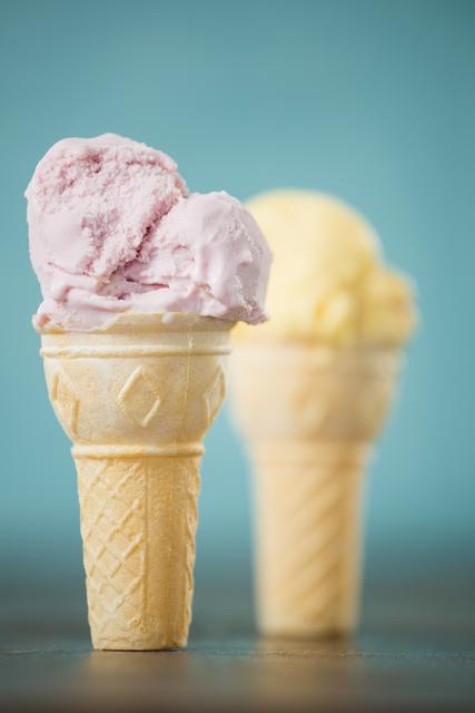 Close-up of strawberry ice cream cone with vanilla ice cream cone in background
