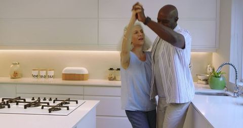 Senior Couple Dancing in Modern Kitchen Reflecting Love