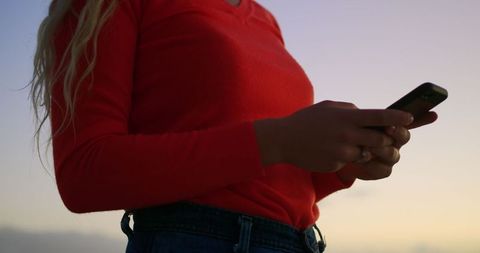 Woman Texting on Smartphone During Twilight Beach Walk