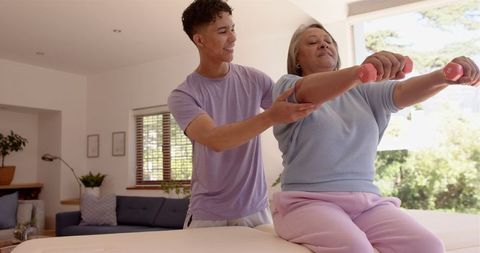 Male Physiotherapist Assisting Senior Woman with Dumbbell Exercises