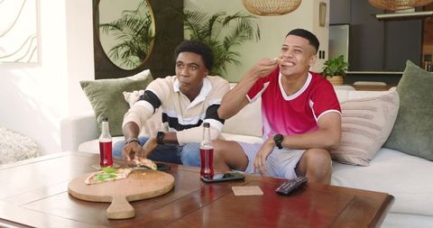 Diverse Friends Enjoying Pizza and Soda on Cozy Living Room Sofa