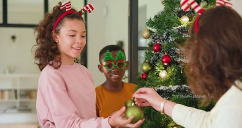Joyful family decorating christmas tree with festive accessories