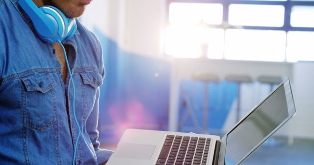 Young man wearing headphones using laptop in modern office space - Download Free Stock Images Pikwizard.com