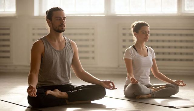 Couple practicing meditation in sunlit yoga studio for mindfulness and wellness