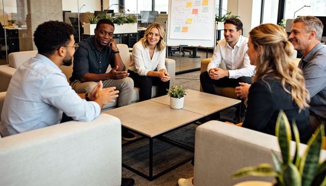 Team collaborating in modern open-plan office lounge during informal brainstorming session