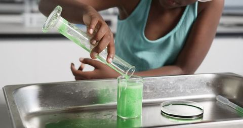 African girl pouring green foam during hands-on school chemistry experiment
