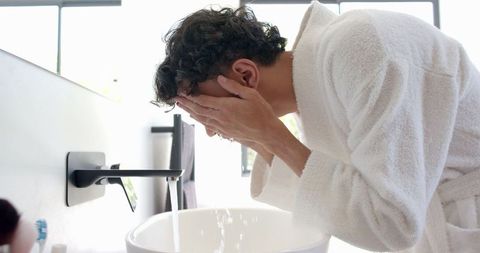 Man Rinsing Face with Water in Modern Bathroom Setting