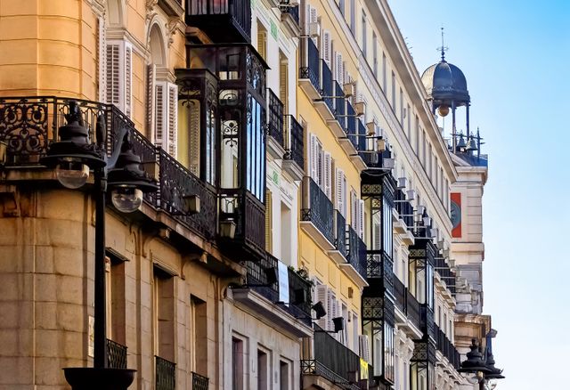 This detailed view of charming apartment buildings in a European city's historical center offers a glimpse of traditional architecture featuring ornate balconies and vintage designs. Ideal for travel magazines, architectural studies, urban development projects, and cultural heritage promotion.