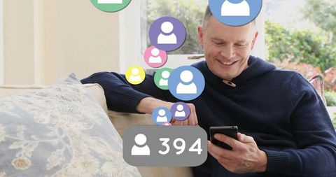 Smiling middle-aged man on sofa checking smartphone with social followers icons and badge