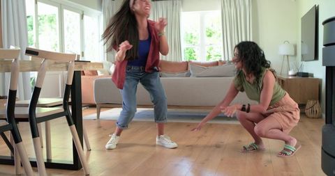 Friends dancing and laughing in bright living room, casual home movement joyful lifestyle
