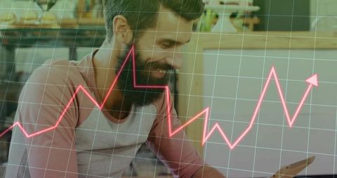 Smiling man in coffee shop analyzing data with tablet