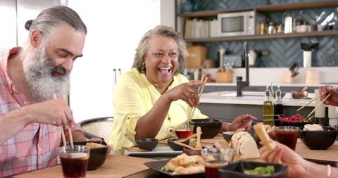 Senior friends sharing laughter and dinner in kitchen