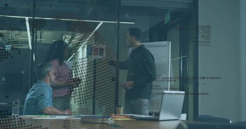 Team collaborating around conference table with sticky notes on dotted glass wall