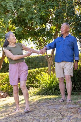 Sunlit garden stroll senior couple holding hands enjoying outdoor companionship and joy