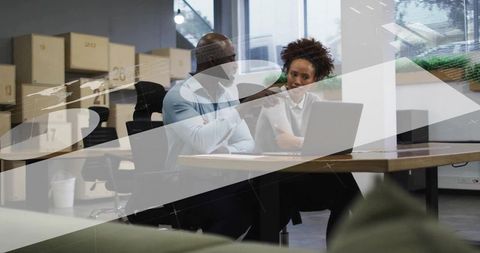 Colleagues Collaborating Over Laptop Amid Storage Boxes Planning Growth in Modern Open-Plan Office