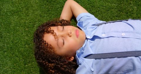Young Boy Relaxing on Grass Under Sunlight
