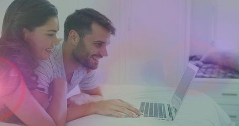 Couple Relaxing in Bedroom Streaming Movie on Laptop Together