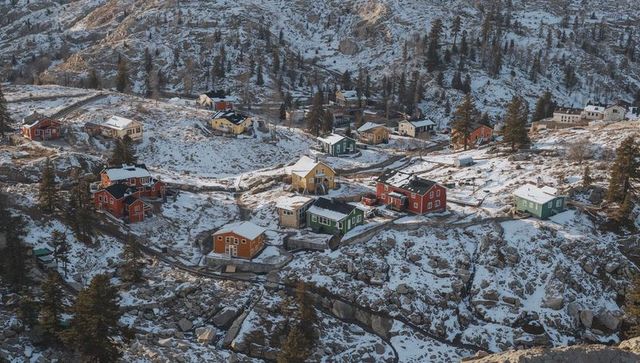 Colorful wooden cabins clinging to snowy rocky alpine slope with terraced paths
