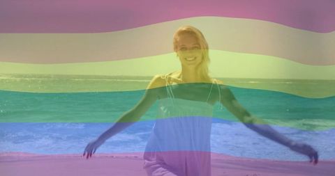 Joyful woman embracing freedom by ocean with rainbow overlay