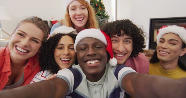 Happy group of diverse friends taking selfie and smiling. Spending quality time at home together at christmas.