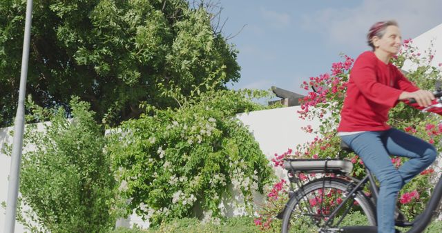 Senior Woman Riding Electric Bike Outdoors Against Floral Garden and Clear Sky - Download Free Stock Images Pikwizard.com