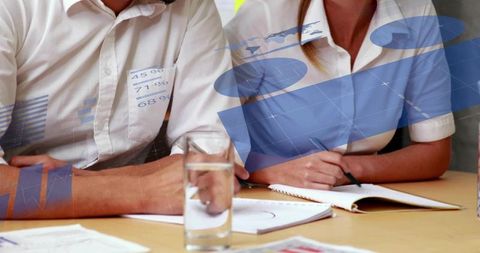 Business professionals taking notes during data-driven meeting with charts and notebooks