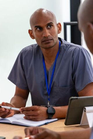 African american physician in scrubs leading focused clinical team meeting with tablet