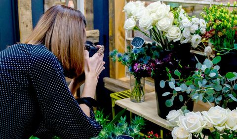 Woman Capturing Floral Arrangements with DSLR at Boutique Flower Market
