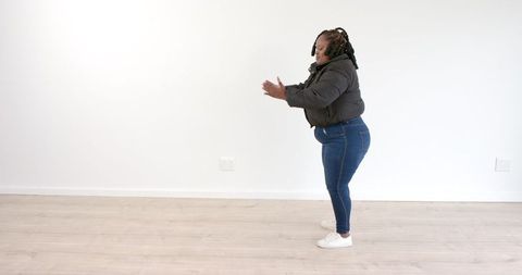 Determined Woman Practicing Squats Alone in Minimal Gym Space